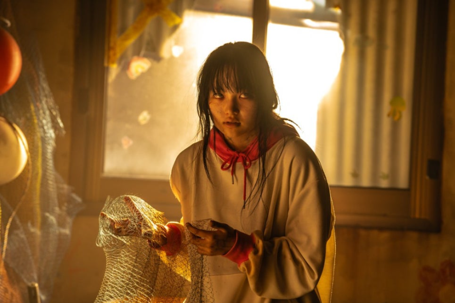 좀비의 모습으로 변해가는 수아. 사람의 눈빛은 없고 무표정한 눈빛으로 노려보고 있다.