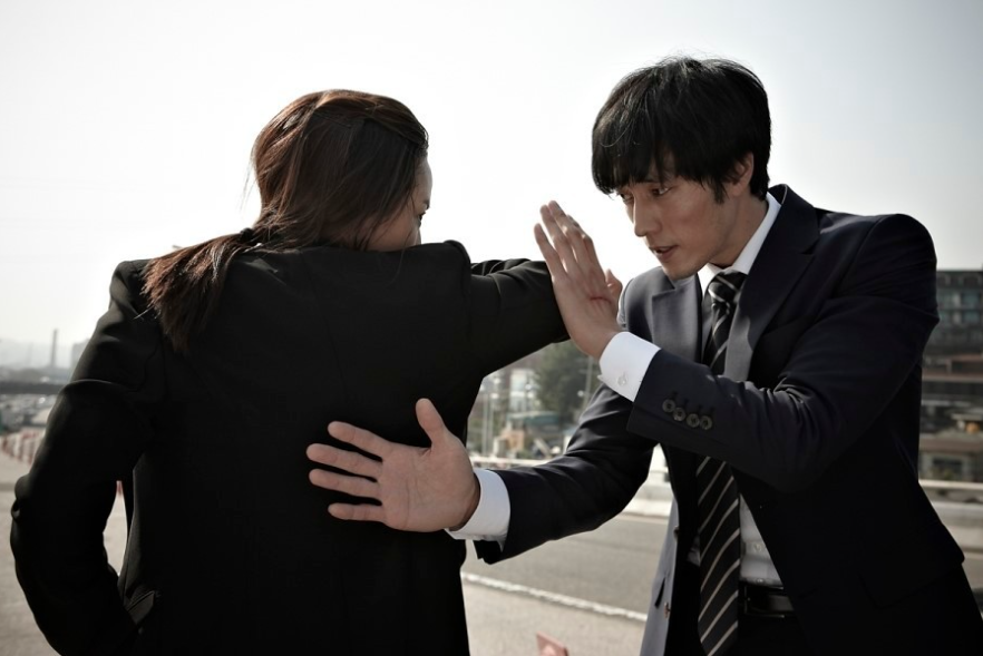 동료와 대로변에서 격투를 벌이고 있는 형도. 회사에서 해고 처분이 내려와 동료들이 형도를 공격하고 있다.