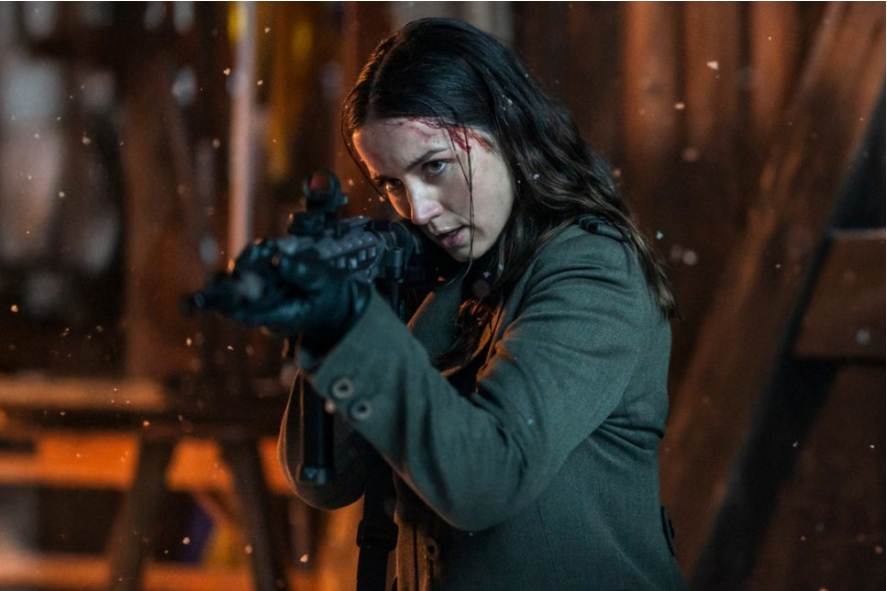 이미지는 영화 **《발레리나》**의 스틸컷으로, 주인공인 루니(아나 데 아르마스)가 총을 조준하고 있는 모습입니다. 머리에는 피가 묻어 있고, 눈이 내리는 듯한 배경에서 긴장감 넘치는 상황을 보여줍니다. 그녀의 표정은 결연하고 전투적인 모습을 드러내며, 영화 속 격렬한 액션 장면의 일부임을 짐작할 수 있습니다.