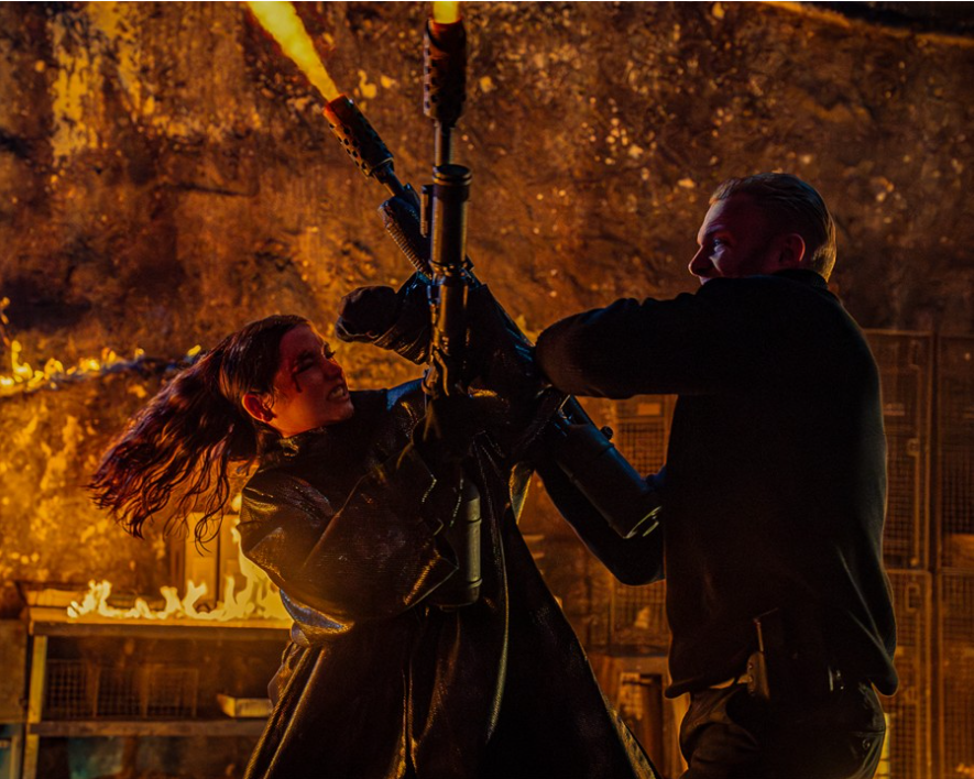 이미지는 영화 **《발레리나》**의 스틸컷입니다. 주인공인 루니(아나 데 아르마스)가 다른 인물과 격렬하게 화염방사기를 두고 몸싸움을 벌이는 장면입니다. 주변의 불길과 그녀의 긴장된 표정은 치열한 전투 상황을 보여주며, 영화의 거친 액션을 짐작하게 합니다.