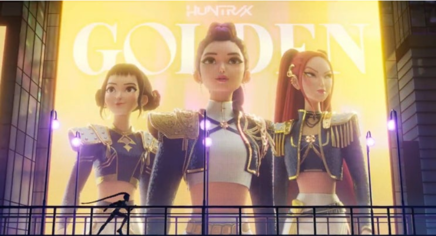 한 도시의 대형 스크린에 세 명의 애니메이션 캐릭터가 서 있는 모습이 보입니다. 그들은 화려한 금색 장식이 있는 어두운 옷을 입고 있으며, 스크린에는 'HUNTRX'와 'GOLDEN'이라는 글자가 적혀 있습니다. 스크린 앞 난간에 작은 인물이 보입니다.