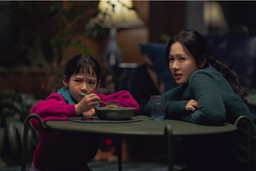 미리(손예진)가 걱정스러운 표정으로 딸 유리원을 바라보고 있으며, 딸은 밥을 먹다가 무언가 불편한 듯한 시선으로 응시하고 있습니다. 어두운 배경 속에서 두 모녀의 복잡한 감정이 드러납니다.