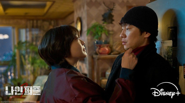 디즈니+ 오리지널 시리즈 '나인 퍼즐' 속 두 주인공의 묘한 긴장감이 흐르는 대치 상황을 담고 있습니다.